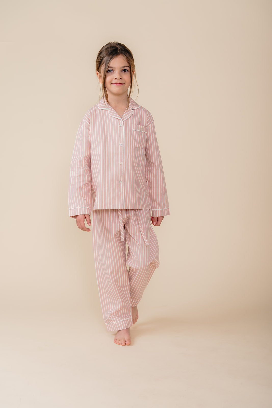 Meisje draagt een roze gestreepte katoenen pyjama uit de Striped Dreams collectie van Atelier Bonheur. Comfortabele en stijlvolle nachtkleding voor kinderen.

