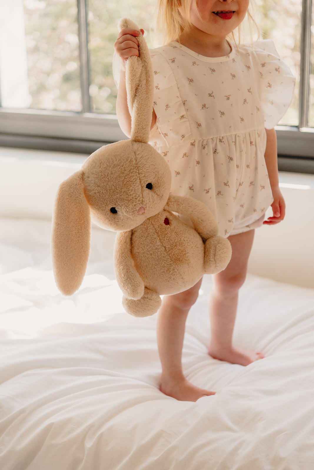 Klein meisje met zachte beige knuffelbeer Boncoeur van Atelier Bonheur, ideaal geboortecadeau en eerste knuffel voor baby’s en kinderen.