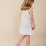 Meisje in witte katoenen pyjama-jurk met bloemenprint uit de Cozy Dawn collectie van Atelier Bonheur, duurzame nachtkleding voor kinderen.