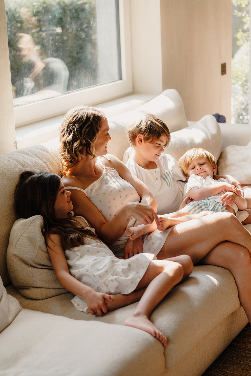 Gezin ontspant samen in de woonkamer in bijpassende Cozy Dawn pyjama’s van Atelier Bonheur, gemaakt van zacht katoen voor verbondenheid en comfort.

