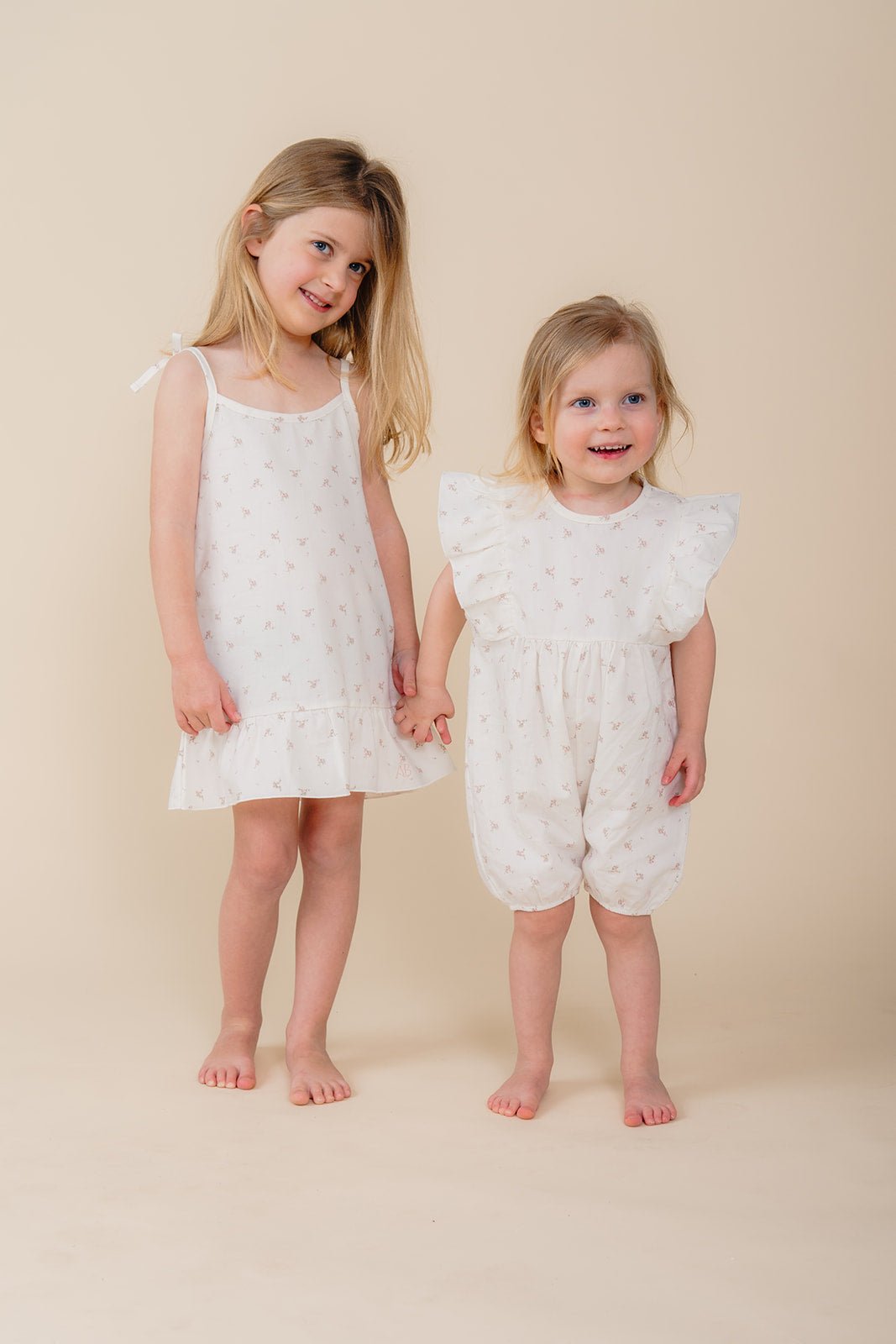 Twee meisjes poseren in lichte bloemenpyjama’s uit de Cozy Dawn collectie van Atelier Bonheur, comfortabele nachtkleding voor kinderen.

