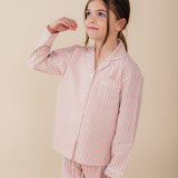 Meisje draagt een roze gestreepte katoenen pyjama uit de Striped Dreams collectie van Atelier Bonheur. Comfortabele en stijlvolle nachtkleding voor kinderen.