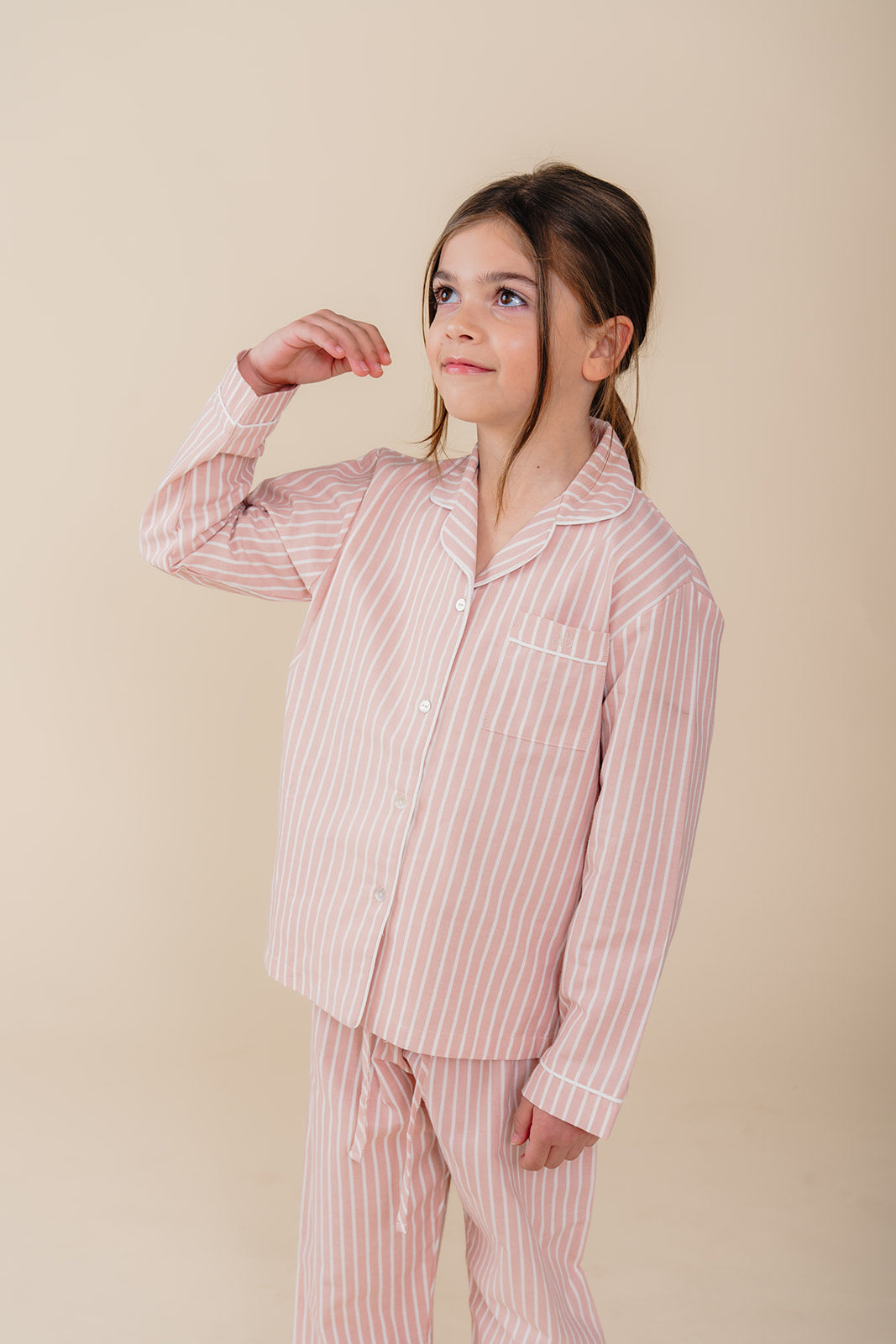 Meisje draagt een roze gestreepte katoenen pyjama uit de Striped Dreams collectie van Atelier Bonheur. Comfortabele en stijlvolle nachtkleding voor kinderen.
