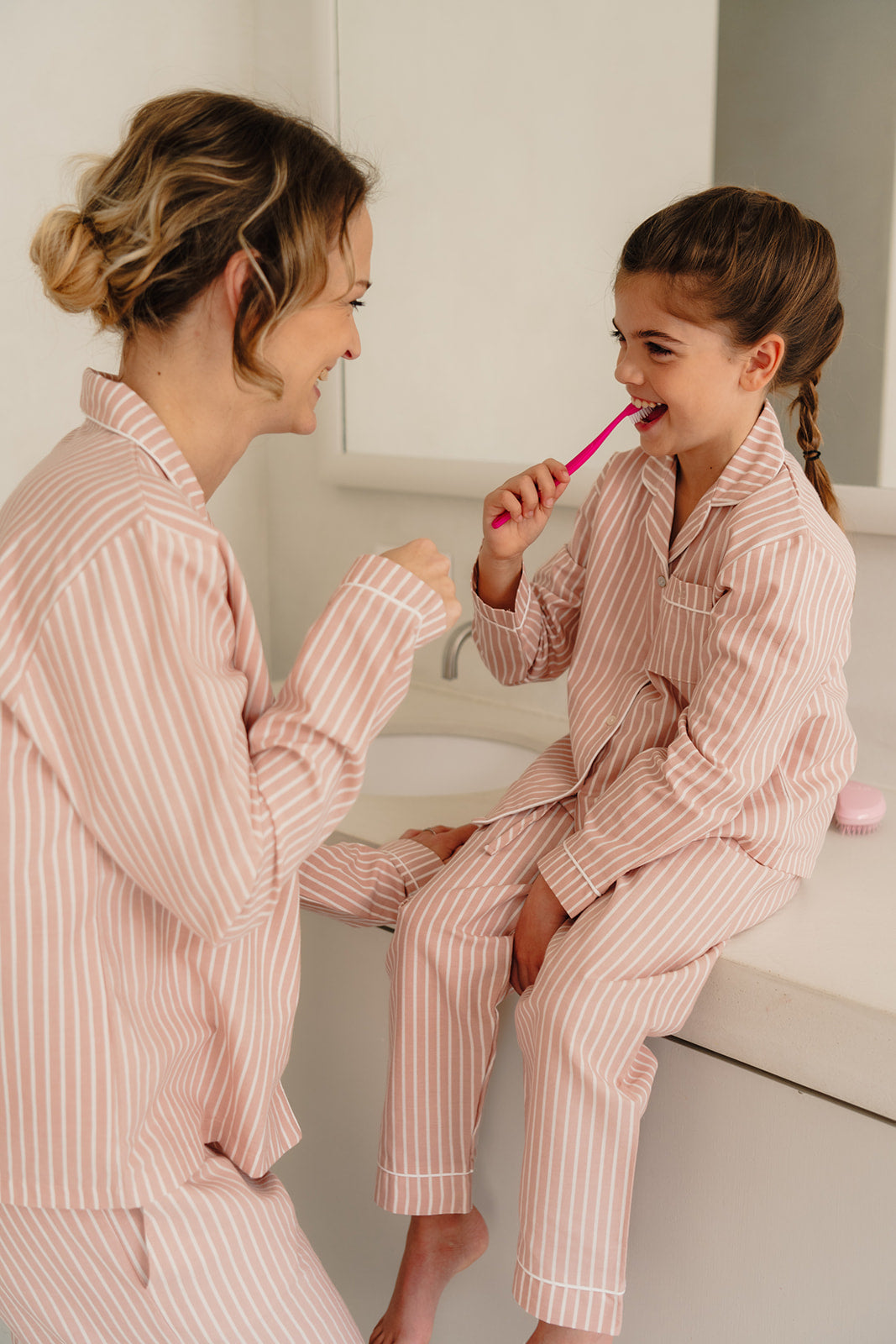 Mama en dochter poetsen samen tanden in atelier bonheur matching gestreepte roze pyjama