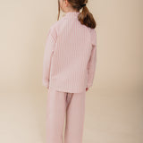 Meisje draagt een roze gestreepte katoenen pyjama uit de Striped Dreams collectie van Atelier Bonheur. Comfortabele en stijlvolle nachtkleding voor kinderen.

