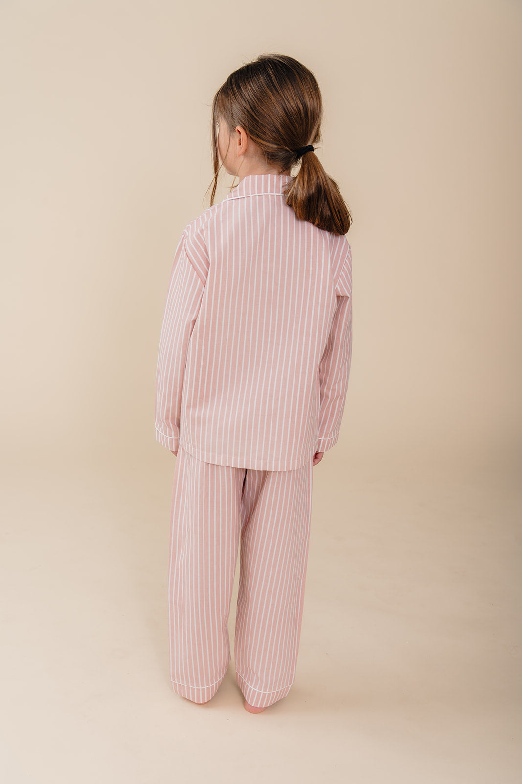 Meisje draagt een roze gestreepte katoenen pyjama uit de Striped Dreams collectie van Atelier Bonheur. Comfortabele en stijlvolle nachtkleding voor kinderen.


