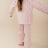 Meisje draagt een roze gestreepte katoenen pyjama uit de Striped Dreams collectie van Atelier Bonheur. Comfortabele en stijlvolle nachtkleding voor kinderen.

